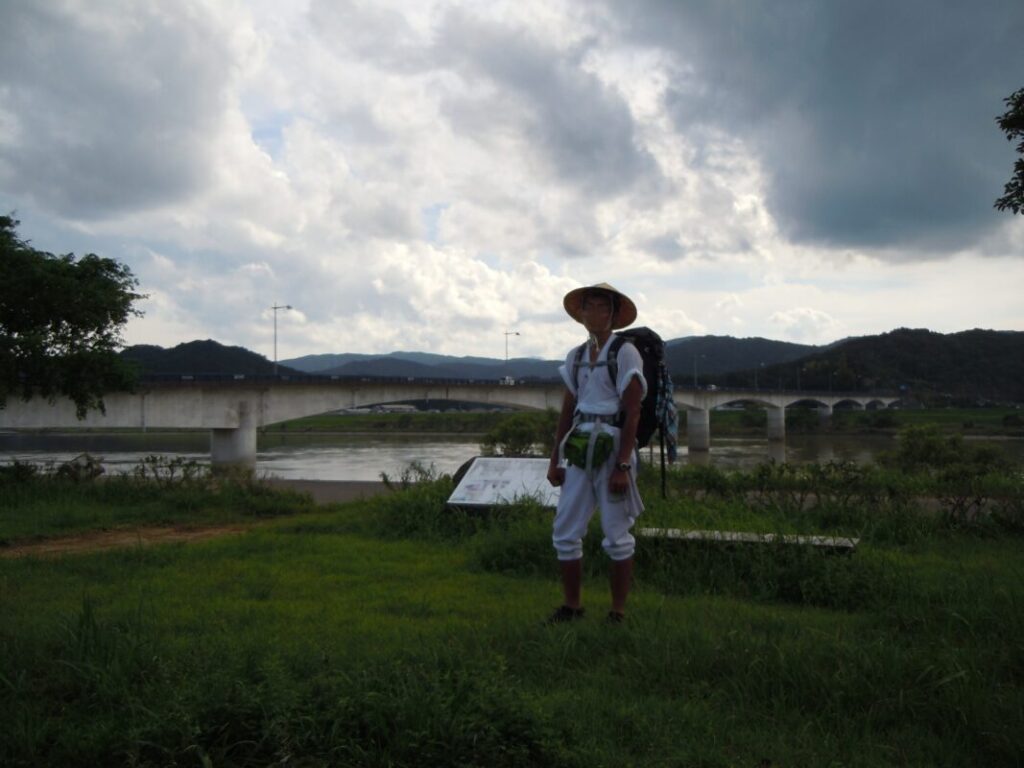 Me in walking pilgrim attire on the Shimanto River riverbank in Kochi during summer
