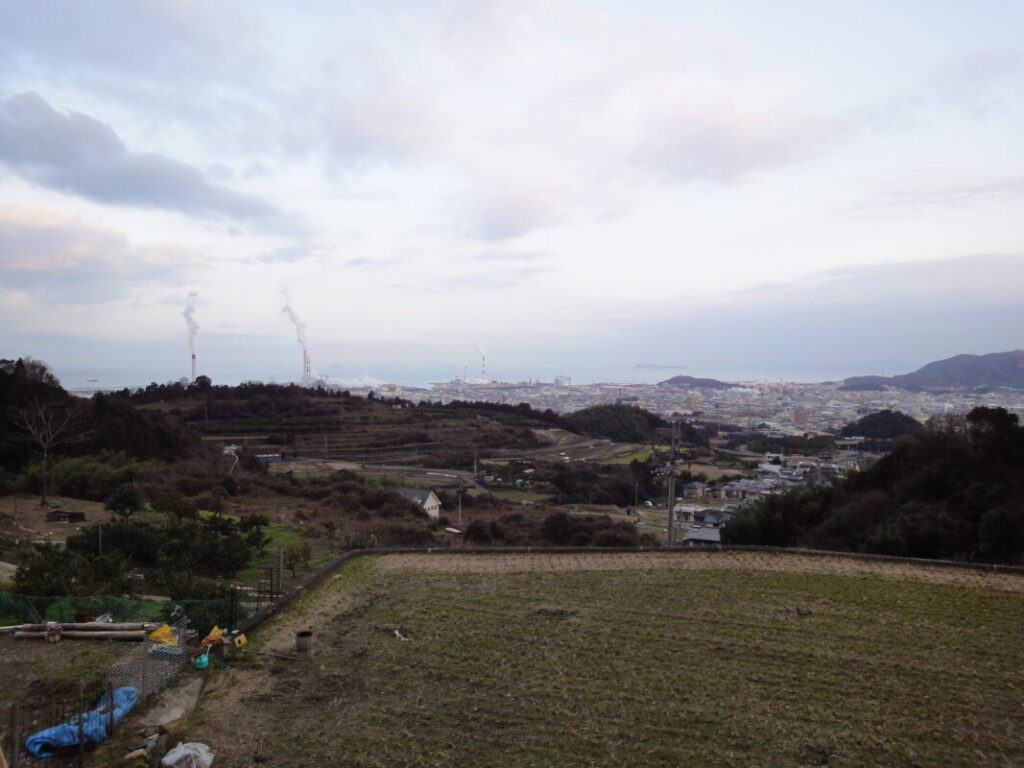 The mountain trail to Sankakuji Temple, with terraced fields and the town below visible in the distance.