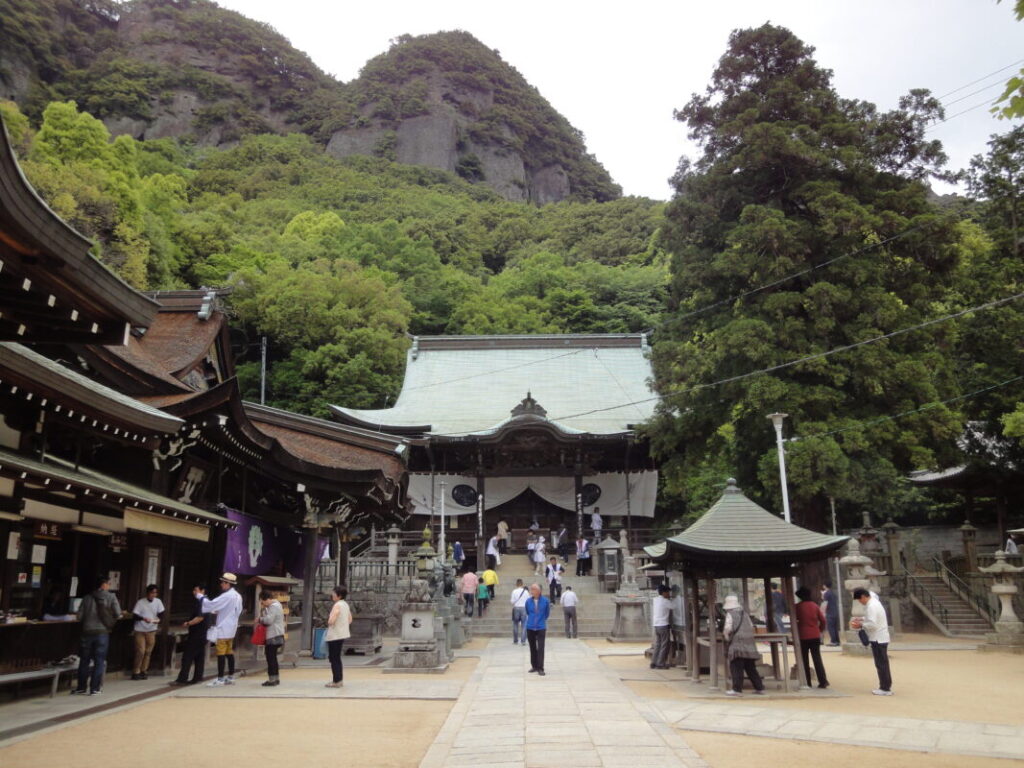The Main Hall of Yaguriji Temple, with the rocky cliffs of Mount Gokenzan rising behind it.